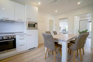 eine Küche mit einem Holztisch und Stühlen in der Unterkunft Sonnenterrasse - Helle & moderne Ferienwohnung am Meer in Nordstrand