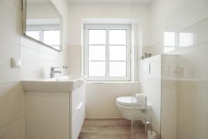 ein weißes Badezimmer mit Waschbecken und Toilette in der Unterkunft Sonnenterrasse - Helle & moderne Ferienwohnung am Meer in Nordstrand + 11 Fotos