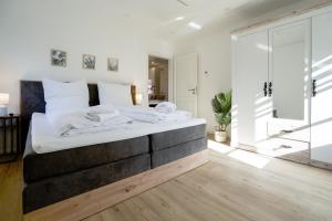 ein Schlafzimmer mit einem großen Bett mit weißer Bettwäsche in der Unterkunft Sonnenterrasse - Helle & moderne Ferienwohnung am Meer in Nordstrand