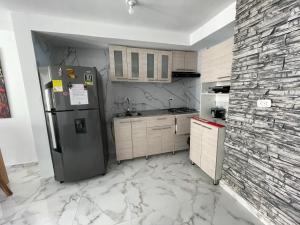 a kitchen with a refrigerator and a stone wall at Fontana campestre in Ibagué