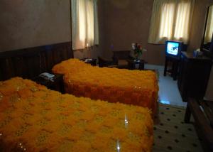 a hotel room with two beds and a television at Hotel Ksar Kaissar in El Kelaa des Mgouna