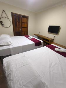 una habitación de hotel con dos camas y un televisor de pantalla plana en Vila Bahia suítes, en Caraíva