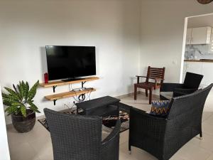 a living room with a table and chairs and a flat screen tv at Maison de vacances à Deshaies 971 in Deshaies