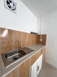 a kitchen with a stainless steel sink and wooden cabinets at Tim House Thalang Phuket in Thalang +11 photos