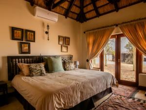 ein Schlafzimmer mit einem Bett und einem großen Fenster in der Unterkunft Zebula Golf and Wildlife Estate - Owl's Haven Pax 10 - Moi Signature Luxury villa in Mabula