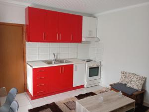 a kitchen with red cabinets and a sink and a table at Vasilikis House in Mángana