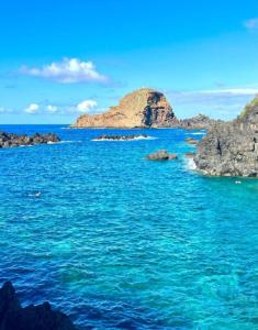 an island in the ocean with blue water and rocks at Village Sun House - Porto Moniz in Porto Moniz
