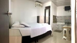 a white bedroom with a bed and a bathroom at Hotel La Herradura in Puerto López