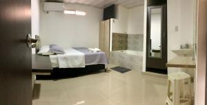a bedroom with a bed and a bathroom with a sink at Hotel La Herradura in Puerto López