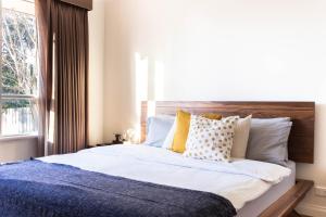 a bedroom with a bed with pillows and a window at Puddings Tranquil Sunroom Retreat in Glen Waverley in Glen Waverley