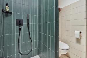 a green tiled bathroom with a shower with a hose at Aparthotel Adagio London City East in London