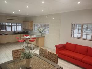 un salon avec un canapé rouge et une cuisine dans l'établissement Majestic Manor Guesthouse & Coffee Shop, à Bloemfontein