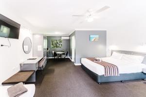 a hotel room with two beds and a desk at Country 2 Coast Motor Inn Coffs Harbour in Coffs Harbour