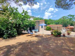 a patio with two chairs and a table and an umbrella at Villa dei Cavallucci Marini in Capoliveri