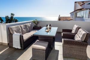 a patio with a couch and chairs and a table at Stunning Beachfront Penthouse in Estepona