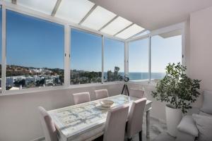 a dining room with a table and chairs and large windows at Stunning Beachfront Penthouse in Estepona +26 photos