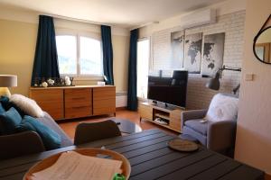 a living room with a couch and a tv at Appartement piscine mer montagne in Les Issambres