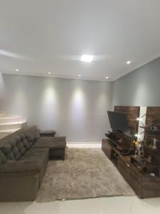 a living room with a couch and a television at Quarto Privativo Santa Rita do Sapucaí in Santa Rita do Sapucaí