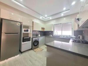 una cocina con frigorífico de acero inoxidable y lavavajillas en VILLA midoun, en Taguermess