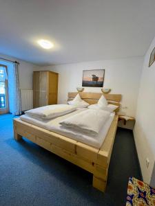 a bedroom with a wooden bed with white sheets at Bergbauernhof Klauslehen in Ramsau