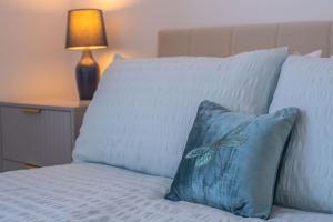 a bed with a blue pillow on it with a lamp at Stylish 3-Bed Home-Liverpool in Liverpool