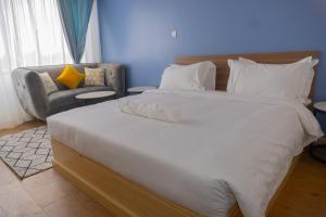 a bedroom with a large white bed and a chair at Laurell Hill Suites, Upper Hill in Nairobi