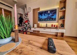 ein Wohnzimmer mit Fernbedienung und einem Weihnachtsbaum in der Unterkunft Apartman Andrea Lux in Zlatibor