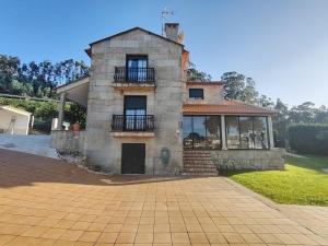 a large stone house with a balcony on a driveway at Villa Alilacha - Piscina Barbacoa Playa 500 m in Bueu