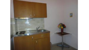 a kitchen with wooden cabinets and a sink and a stool at Galini Sea Apartments in Benitses
