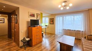 a living room with a television on a dresser with a desk at Green room in Šiauliai