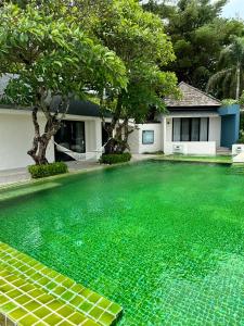 a swimming pool with green water in front of a house at Punnpreeda Beach Resort - SHA Plus Certified in Bangrak Beach