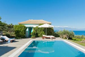 a swimming pool with an umbrella next to a house at The Iconpainter Marathi Villa in Kómboi +8 photos