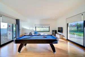 a pool table in a living room with large windows at Binife - Villa exclusiva con piscina climatizada in Alaior