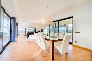 a dining room with a glass table and white chairs at Binife - Villa exclusiva con piscina climatizada in Alaior