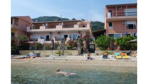a group of people in the water at a beach at Galini Sea Apartments in Benitses