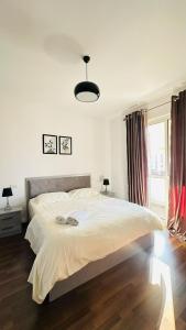 a white bedroom with a large bed and a window at Modern apartment in the heart of Tirana in Tirana