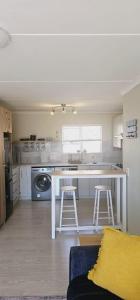 a kitchen with a counter and two stools in it at Breezy Sunny Apartment in Cape Town