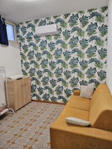 a living room with a couch and palm wallpaper at Tiny house Taormina mare with sofa bed - mini stanza Taormina mare con divano letto in Taormina