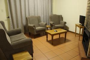 a living room with chairs and a table and a tv at Mogodi Lodge in Graskop