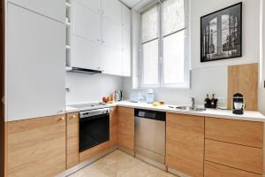 a kitchen with white cabinets and a dishwasher at Luxury Paris, paisible, 2 chambres, toute commodités in Paris