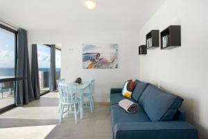 Una sala de estar con un sofá azul y una mesa. en Original Wave House, en Jardim do Mar