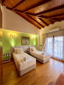 two beds in a room with green walls and wooden floors at Αλσύλλιο - Alsillio studio apartments in Ierissos