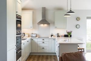 a white kitchen with white cabinets and a counter at Sloopside Apartment in the centre of Bantham with sea views in Bantham