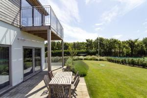 a patio with a wooden table and benches on a lawn at Sloopside Apartment in the centre of Bantham with sea views in Bantham