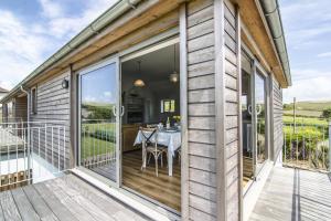 a wooden deck with a table on the side of a house at Sloopside Apartment in the centre of Bantham with sea views in Bantham