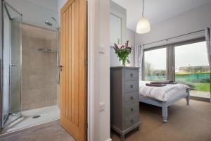 a bedroom with a bed and a glass shower at Sloopside Apartment in the centre of Bantham with sea views in Bantham