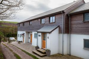 a house with white walls and a brown roof at Sloopside Apartment in the centre of Bantham with sea views in Bantham