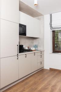 a white kitchen with white cabinets and a wooden floor at Lipowa32 Apartamenty in Hrubieszów