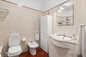 a white bathroom with a toilet and a sink at Casa Oliveira in Conceição +12 photos