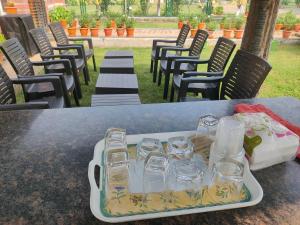 a tray of glasses sitting on a table with chairs at Siva Rama garden resort 6 AC Bed rooms ,swimming pool ,BoX cricket ,Born fair,BBQ, kichan&all, near beach road bheemilli vishakapatnam in Visakhapatnam